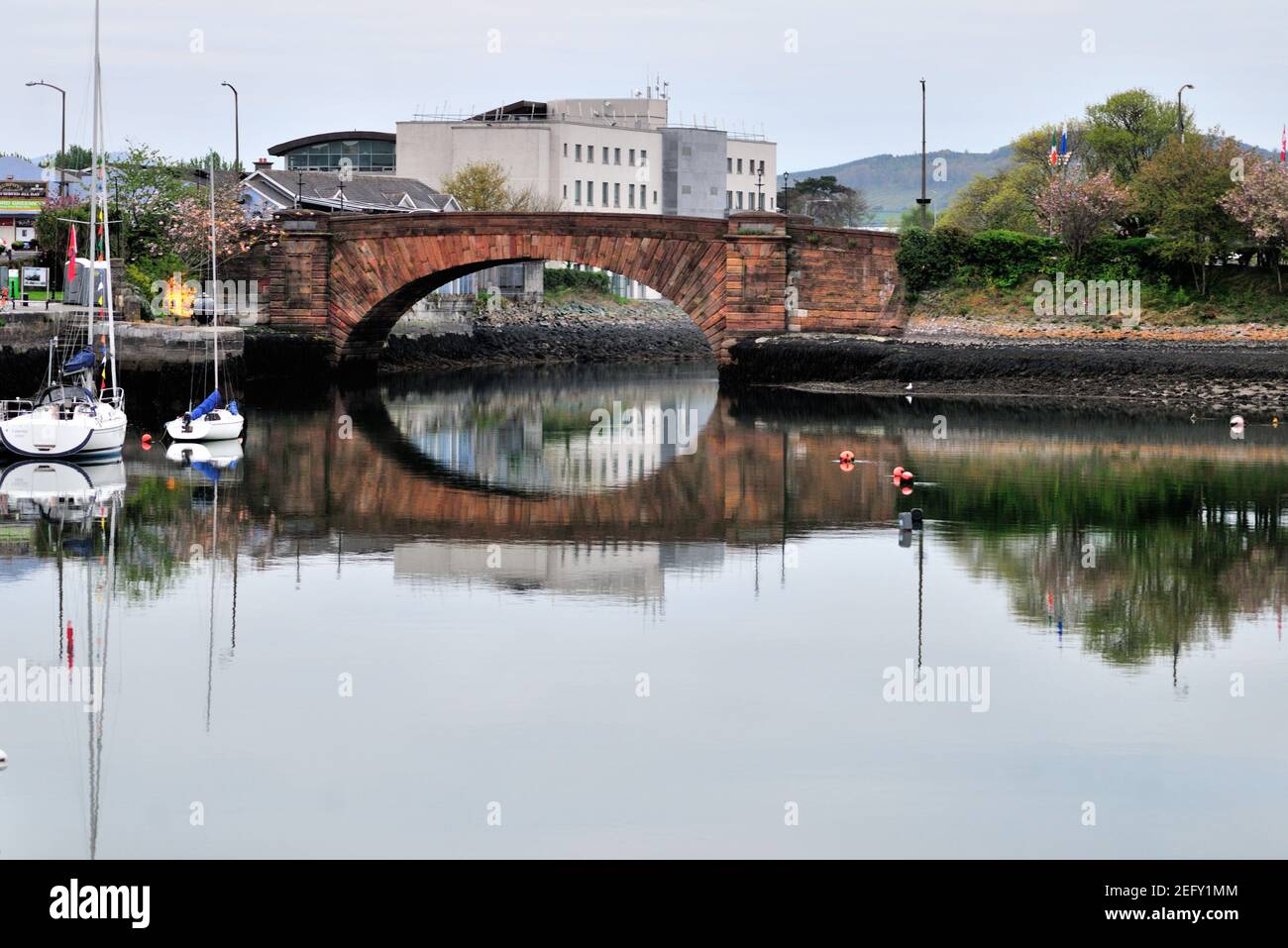 Dungarvan, County Waterford, Irlanda. Le barche a vela aiutano a incorniciare un ponte sulla strada rialzata in un porto colorato nella comunità costiera irlandese di Dungarvan. Foto Stock