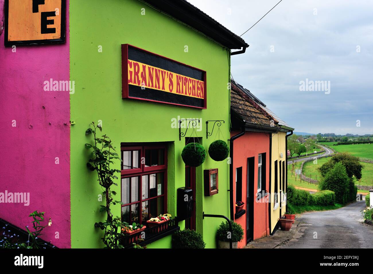 Cashel, County Tipperary, Irlanda. Edifici colorati lungo una strada tortuosa che percorre la campagna irlandese. Foto Stock
