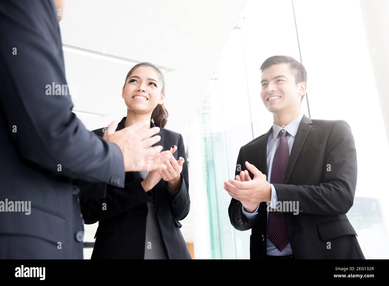 Gli uomini d'affari si aggrappano le mani alla costruzione del corridoio - lodando, congratulandosi e apprezzando i concetti Foto Stock