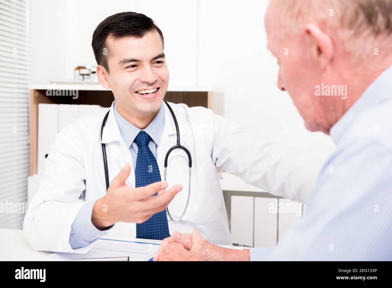 Sorridente medico di consulenza con paziente di sesso maschile senior Foto Stock