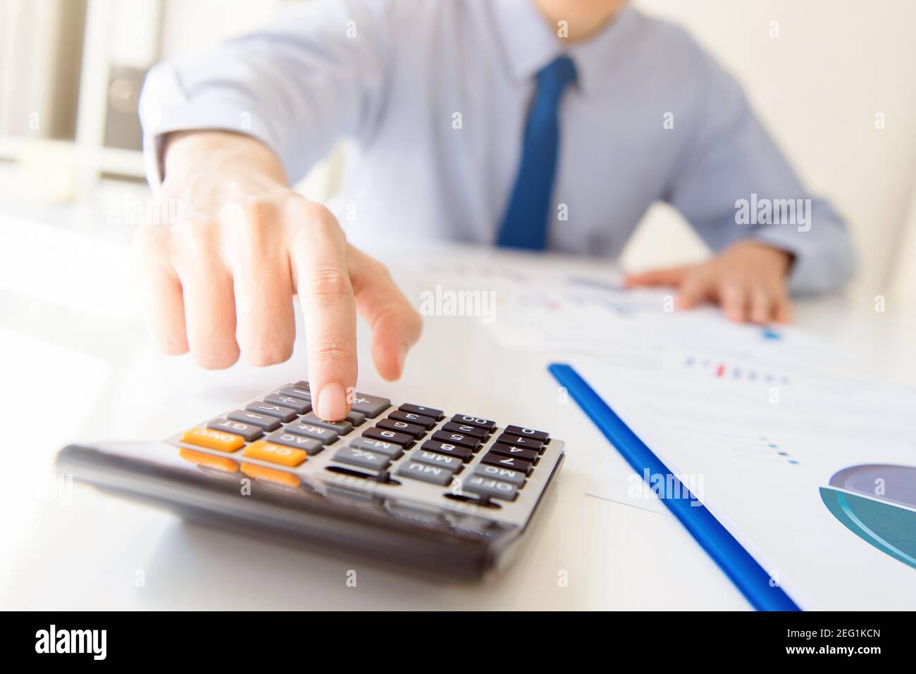 Uomo d'affari premendo il tasto della calcolatrice sul tavolo di lavoro in ufficio - concetto di analisi finanziaria Foto Stock