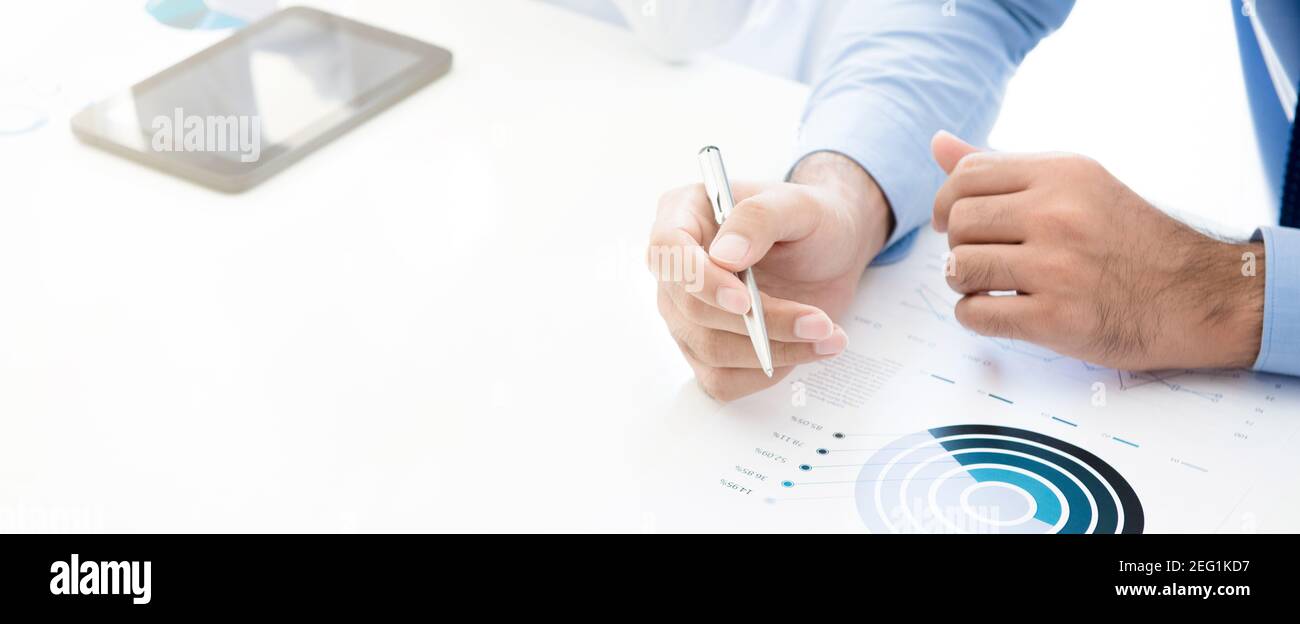 Uomo d'affari che tiene la penna durante la lettura del grafico statistico sul tavolo da lavoro bianco, banner panoramico Foto Stock