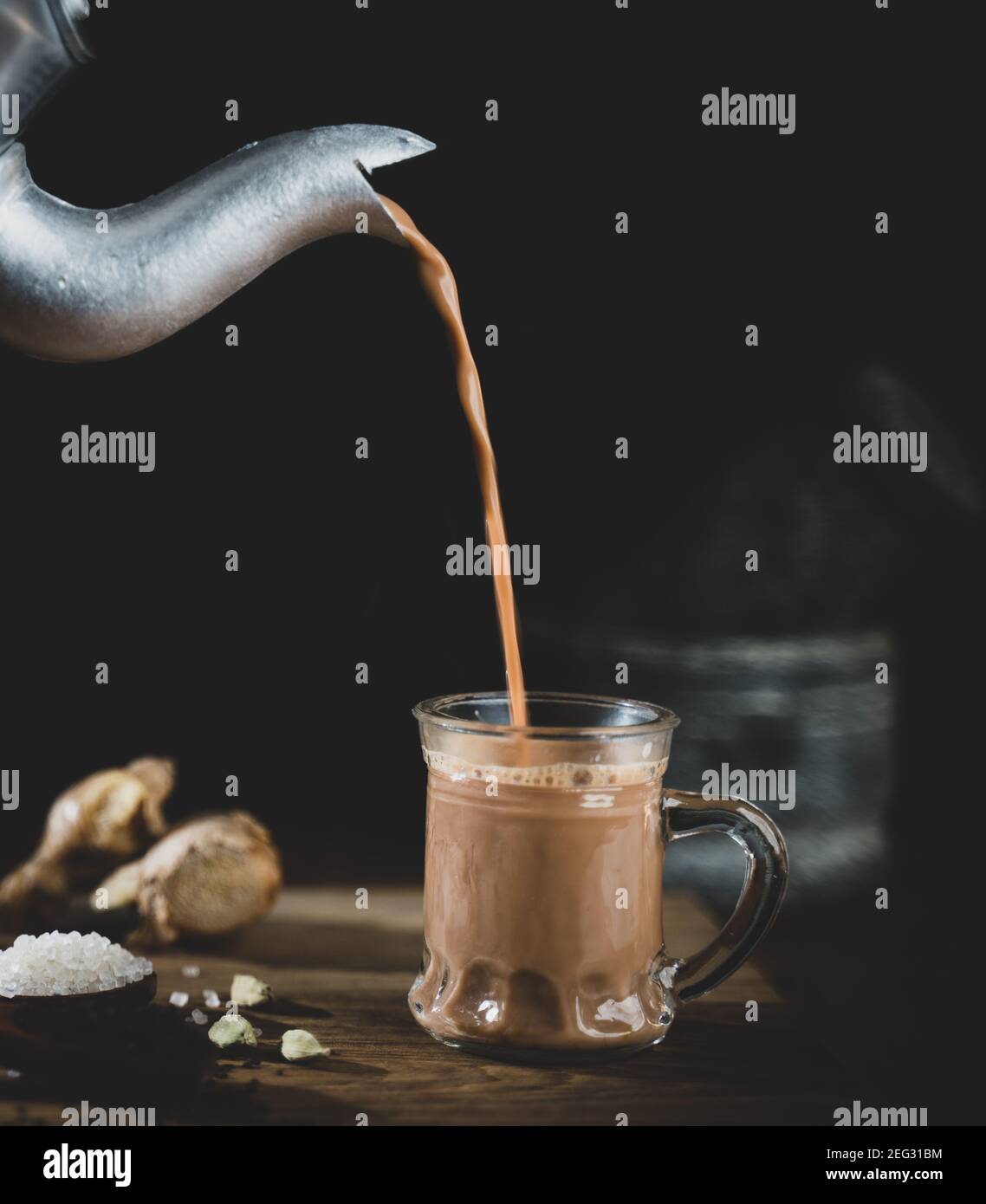 Versare il tè nella tazza di vetro - concetto di ingredienti masala richiesto per la preparazione del tè con aspetto vintage. Foto Stock