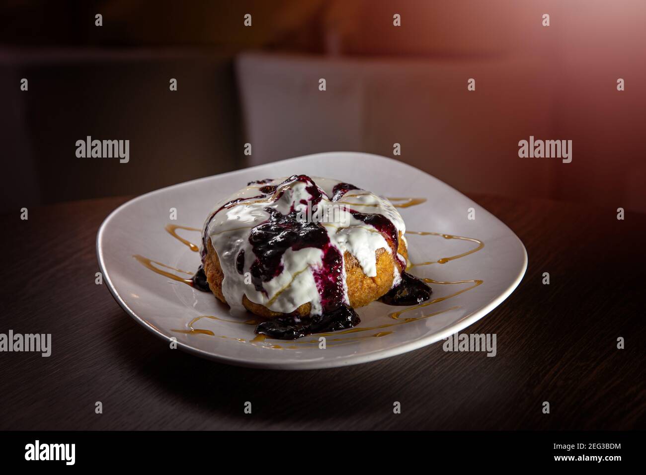 Autentiche ciambelle di formaggio rumeno chiamato papanasi fatto con formaggio casolare e condito con panna acida e con confettura di mirtilli Foto Stock