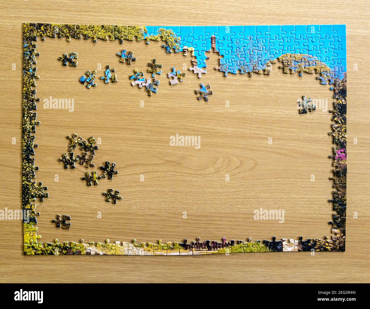 Puzzle nelle fasi iniziali di essere messi insieme su un tavolo di legno, durante il blocco Covid-19. Foto Stock