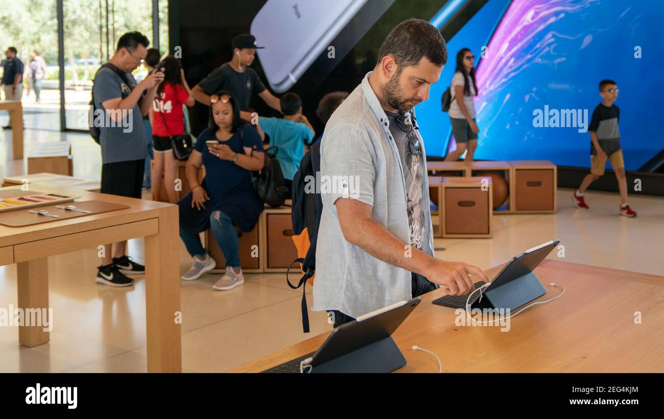 Cupertino, CA, USA - Agosto 2019: Uomo che esamina un iPad in Apple Store a Cupertino, loop infinito sede Apple Foto Stock