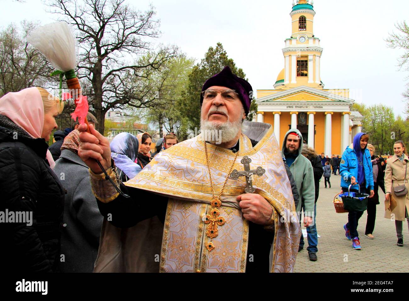 Il sacerdote ortodosso spara i parrocchiani a Pasqua vicino alla chiesa. Rito religioso, festa Battesimo vicino alla cattedrale cristiana. Dnipro città, Dnepr Foto Stock