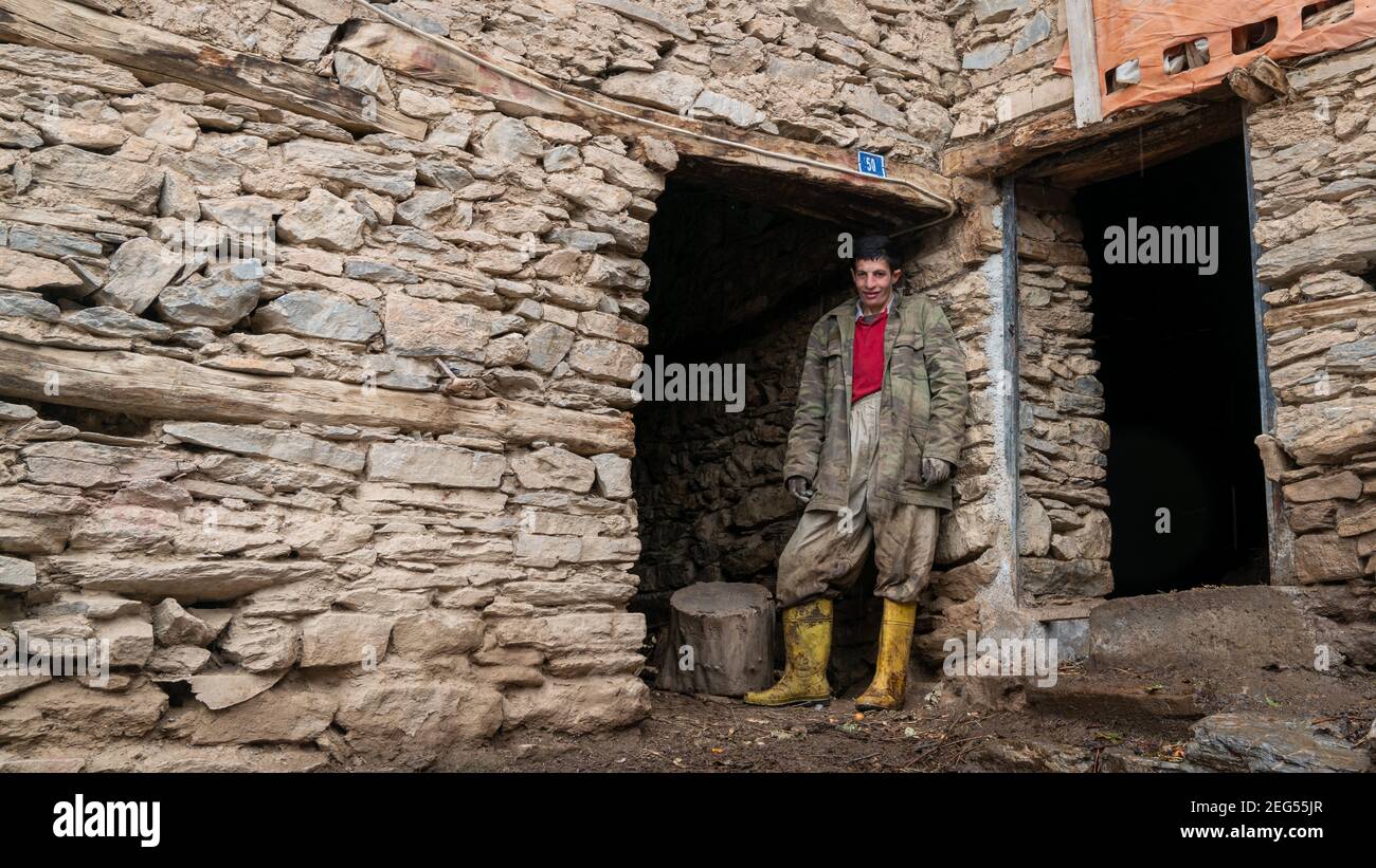 Hizan, Bitlis, Turchia - Febbraio 2020: Giovane uomo in piedi presso una casa di pietra, in Hizan, un villaggio remoto nella Turchia orientale Foto Stock