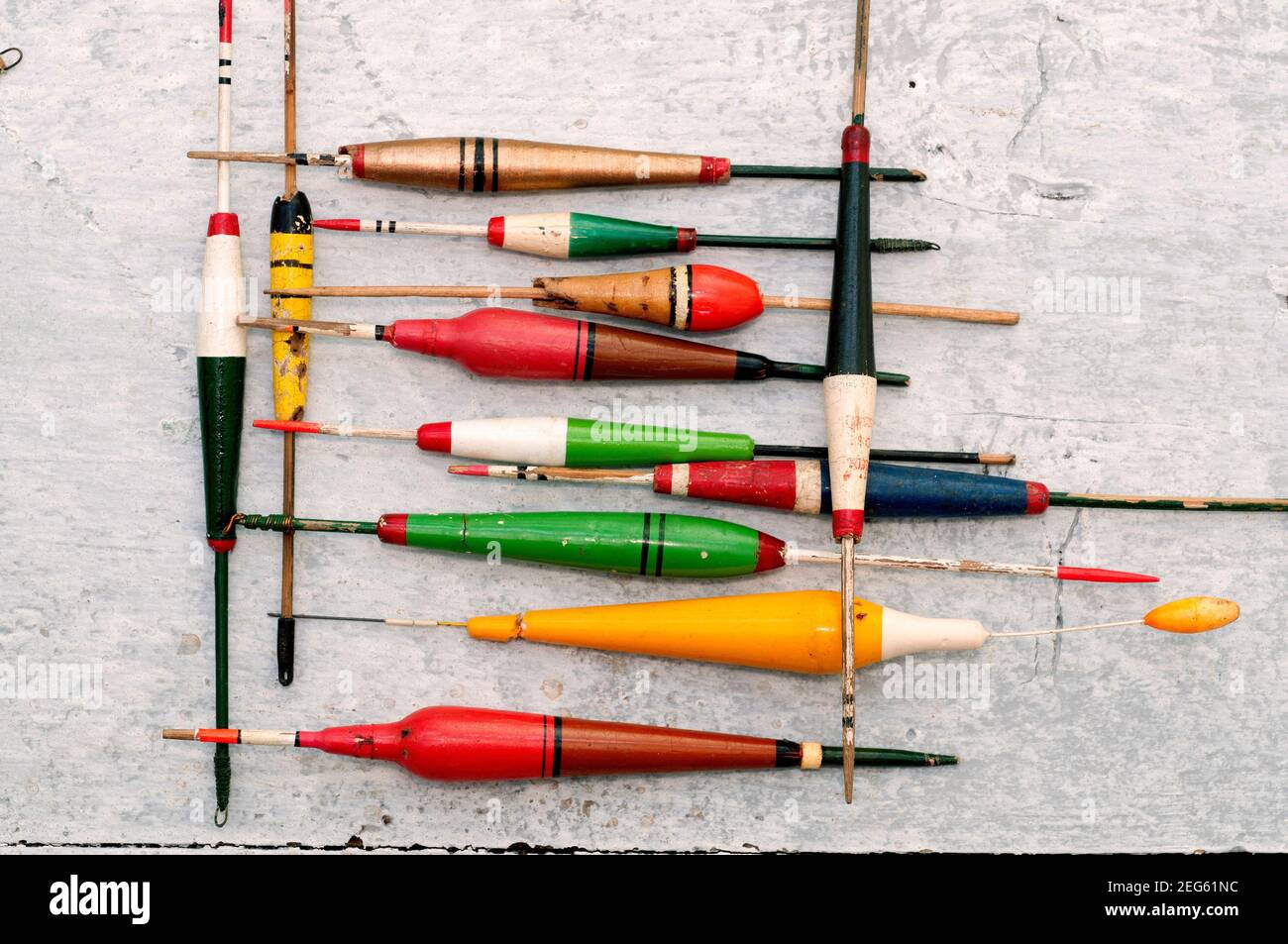 Galleggianti colorati disposti ordinatamente su una superficie di legno per i pescatori tra cui scegliere durante una battuta di pesca Foto Stock
