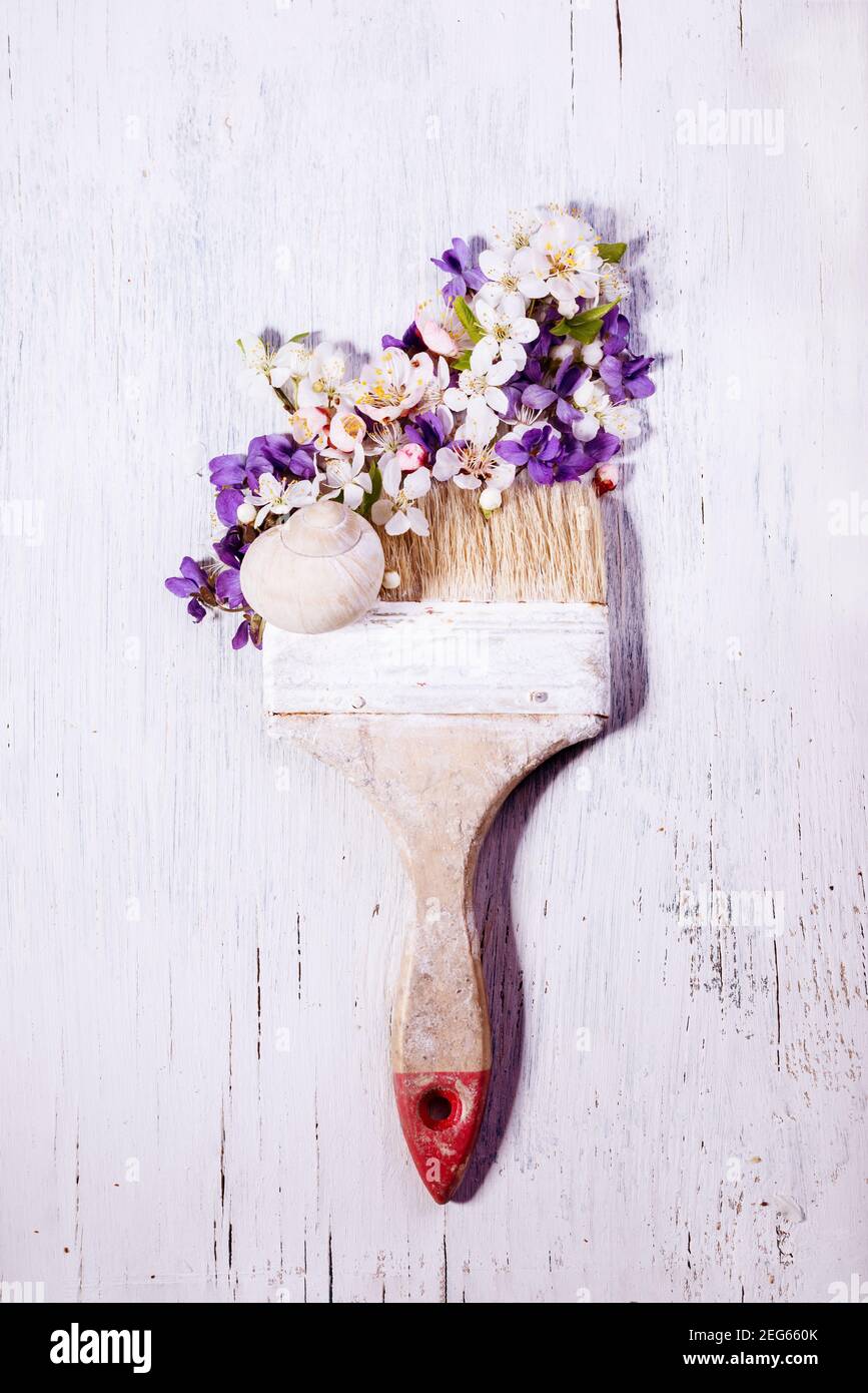 Disegno vintage di pennelli sporchi con bellissimi primi fiori primaverili, violetti e fiori di ciliegio su un tavolo bianco rustico in legno. Foto Stock