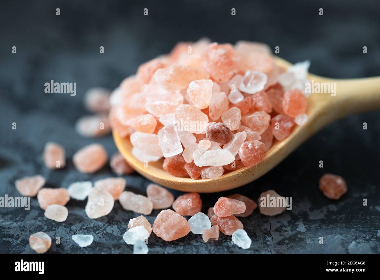 Sale rosa dell'Himalaya nel cucchiaio di legno sul tavolo scuro. Vista ravvicinata. Foto Stock