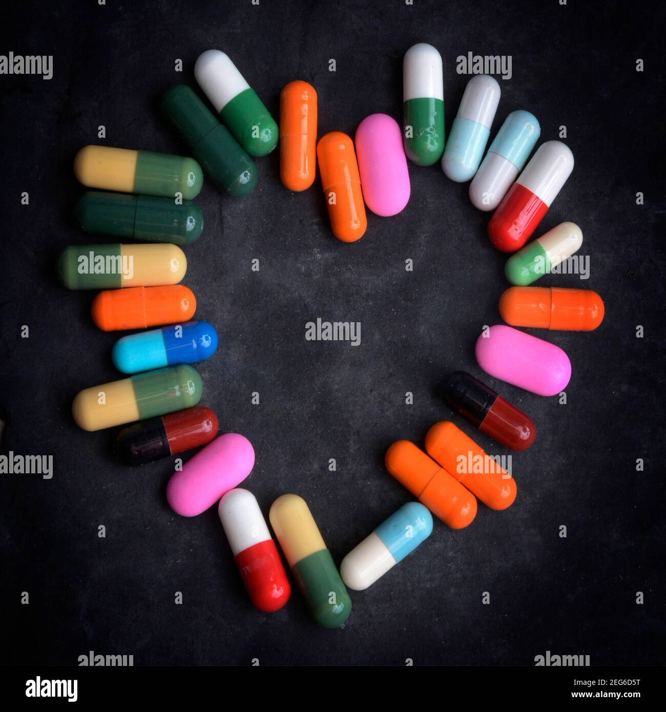 Capsule multiple disposte a forma di cuore su uno sfondo scuro che mostra l'affetto per la salute e il benessere Foto Stock
