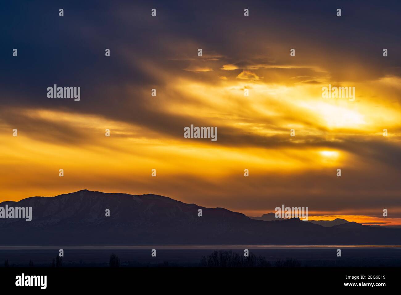 Il sole tramontante illumina le nuvole sopra l'Antelope Island state Park, visto da Layton, Utah, USA. Foto Stock