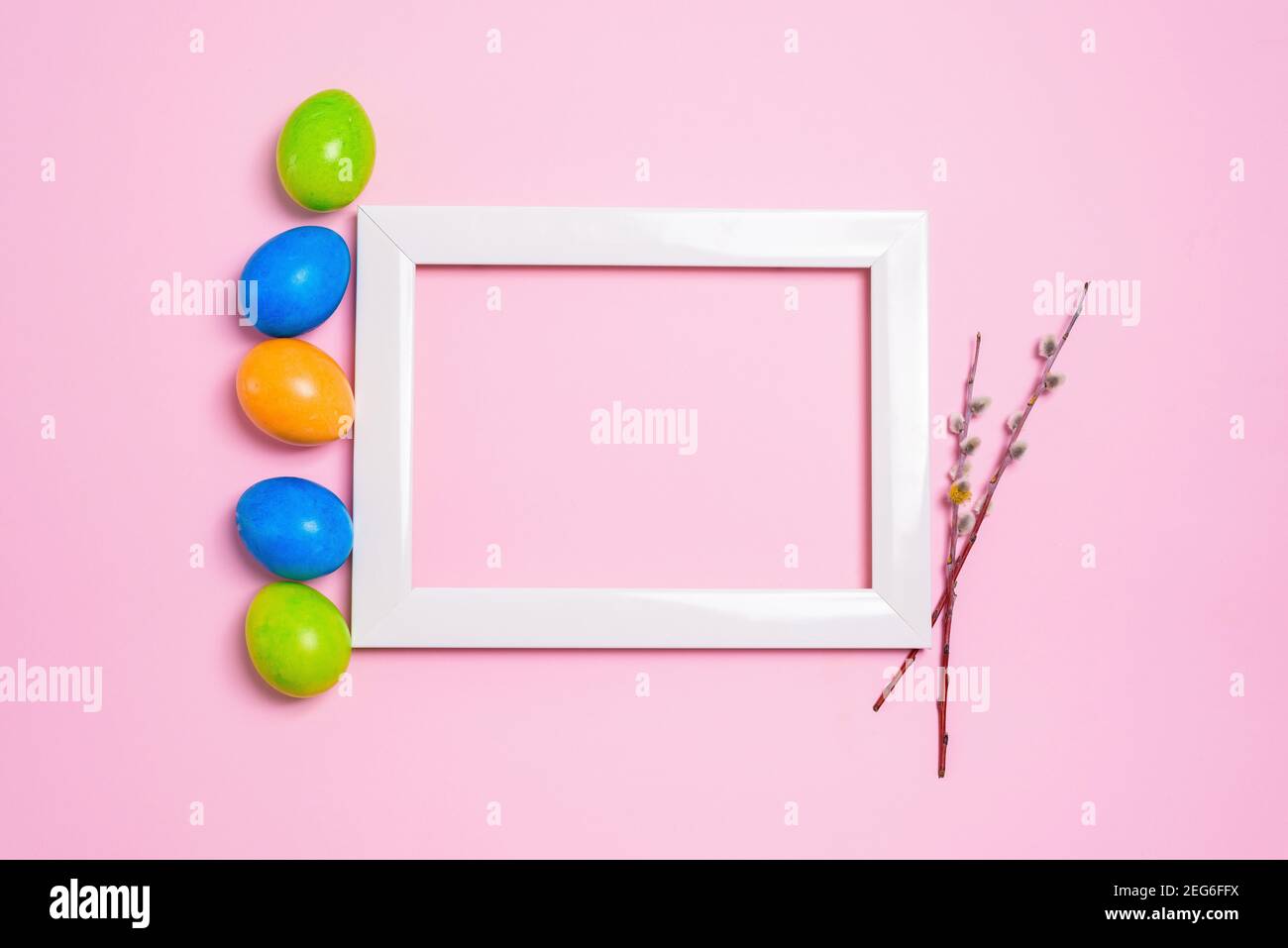 pasqua vacanza salice rami e colorato uovo dipinto cornice foto su uno sfondo rosa pastello. composizione pasqua. Foto Stock