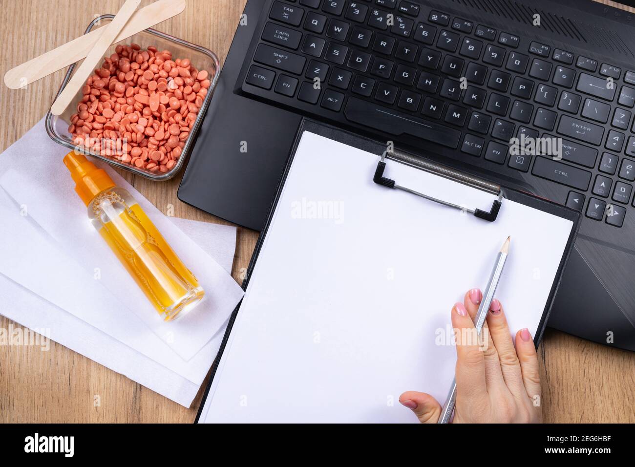 Procedura igienica, concetto di depilazione. Sfondo cosmetico delle mani femminili che fanno note, controllando le informazioni sul portatile, spiegando i dettagli Foto Stock