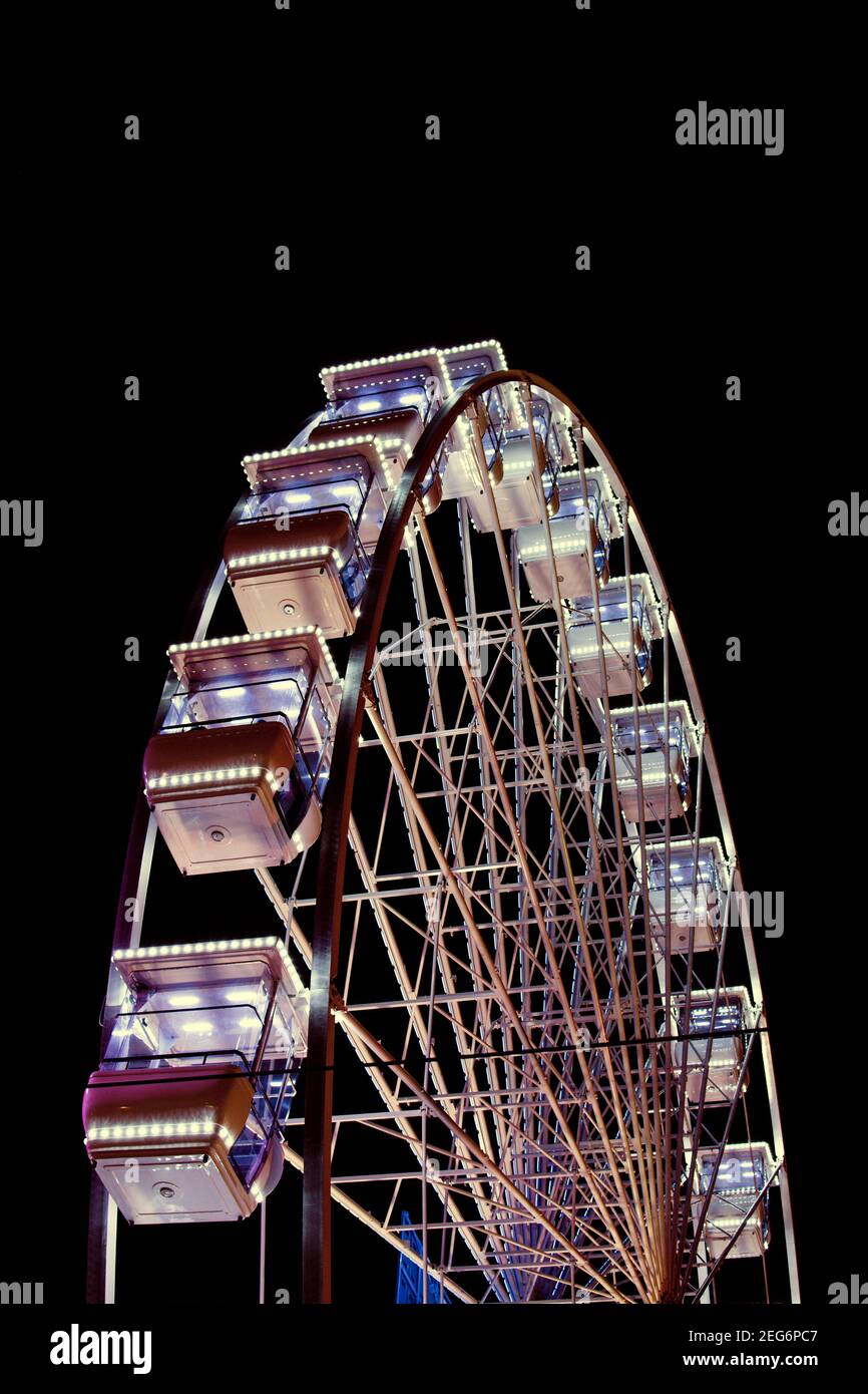 Maestosa ruota panoramica illuminata di notte in un vivace parco divertimenti Foto Stock