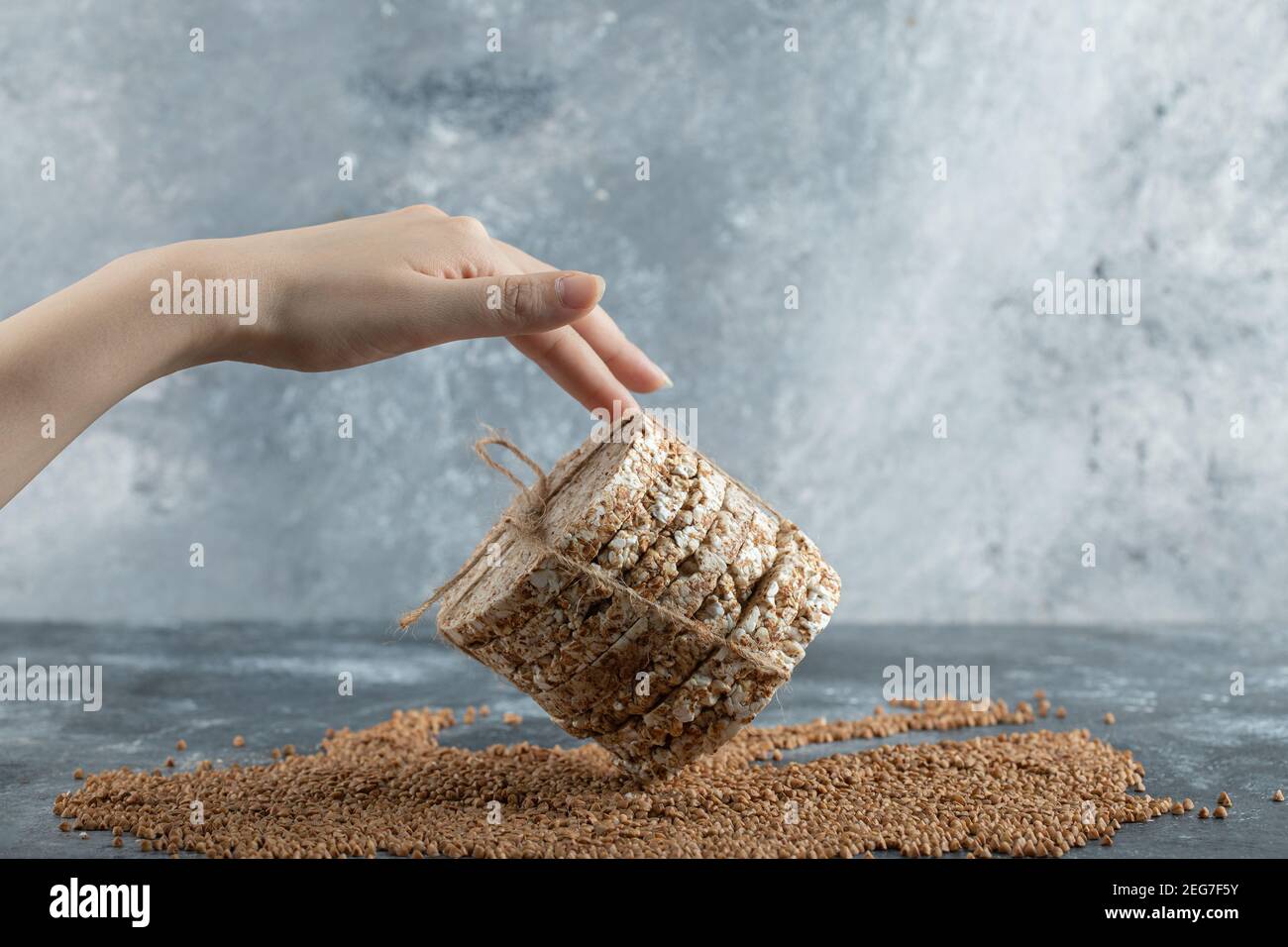 Le mani femminili toccano la torta di riso su sfondo marmoreo Foto Stock