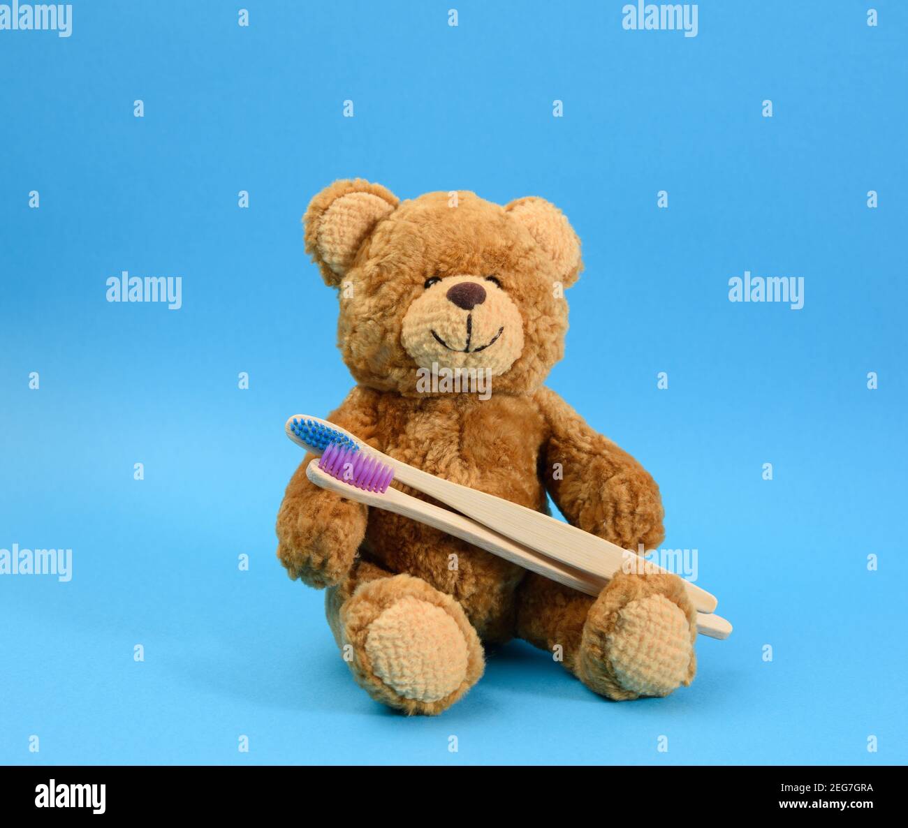 orsacchiotto marrone con spazzolino da denti in legno su sfondo blu, odontoiatria e igiene per bambini Foto Stock