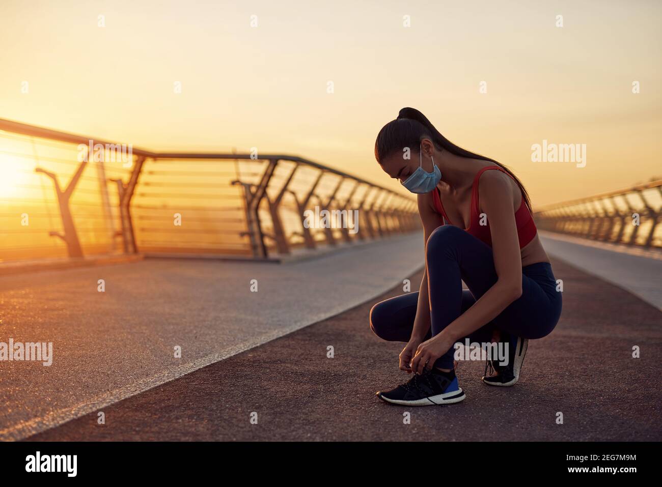 Esercizi mattutini di sicurezza in condizioni di quarantena. Ragazza attenta che si prepara al jogging. Esercitazioni mattutine all'alba Foto Stock