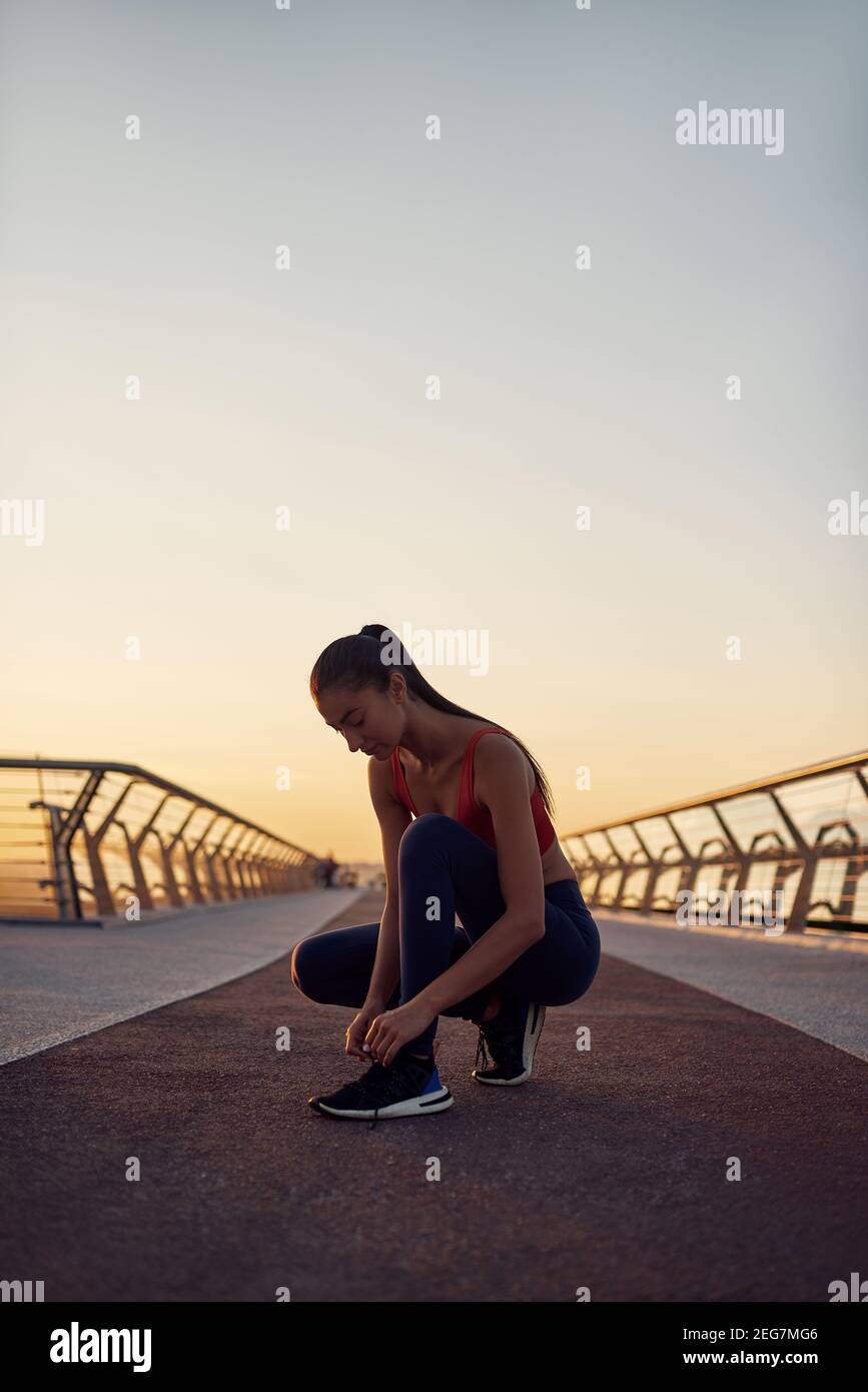 Esercizi mattutini di sicurezza in condizioni di quarantena. Ragazza attenta che si prepara al jogging. Esercitazioni mattutine all'alba Foto Stock