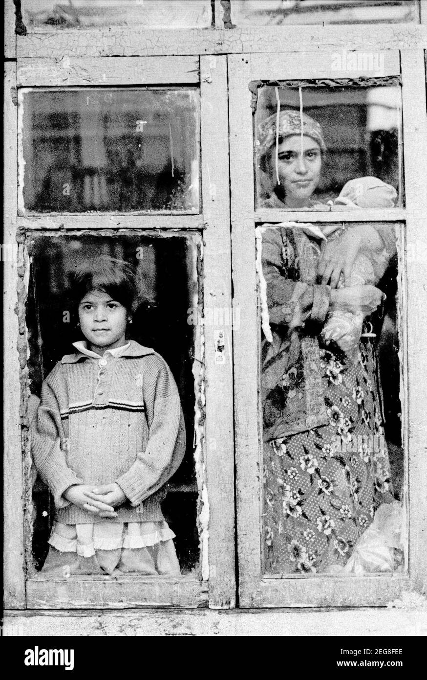 Tashkent, Uzbekistan. Settembre 1999. Una donna ROM, gitana, con il suo bambino tra le braccia e la sorella si affacciano dalle finestre della loro casa in Asia centrale, ex Repubblica sovietica. Foto Stock