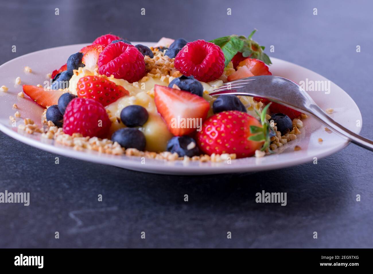 un piatto con budino di vaniglia e frutti di bosco freschi Foto Stock