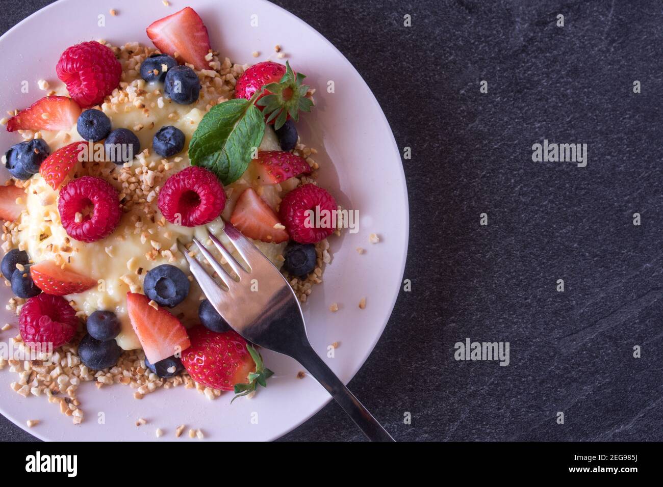 Pudding di proteine alla vaniglia senza zucchero con frutti di bosco freschi e tostati mandorle su un piatto Foto Stock