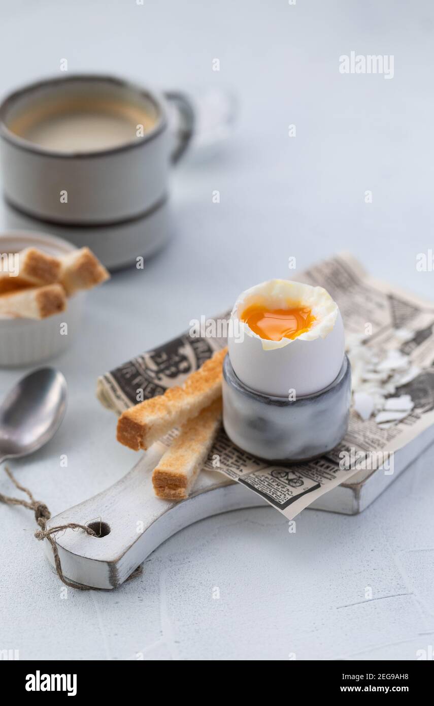 Uova sode in una tazza di uova con toast e caffè sullo sfondo di legno Foto Stock