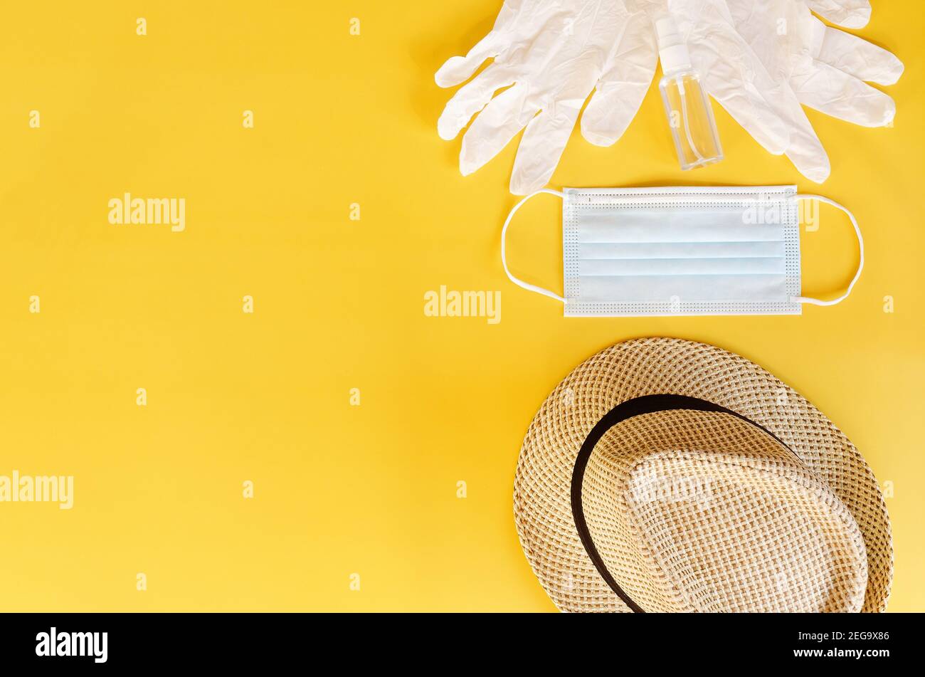 Viaggio dopo Covid-19 e nuovi concetti normali. Vista dall'alto della maschera medica, guanti, cuffie con telefono e cappello da spiaggia su sfondo giallo vicino u Foto Stock