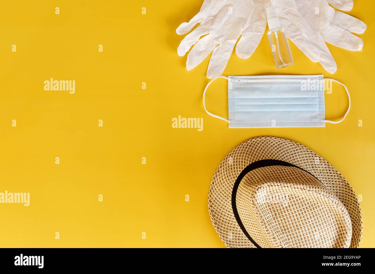 Viaggio dopo Covid-19 e nuovi concetti normali. Vista dall'alto della maschera medica, guanti, cuffie con telefono e cappello da spiaggia su sfondo giallo vicino u Foto Stock