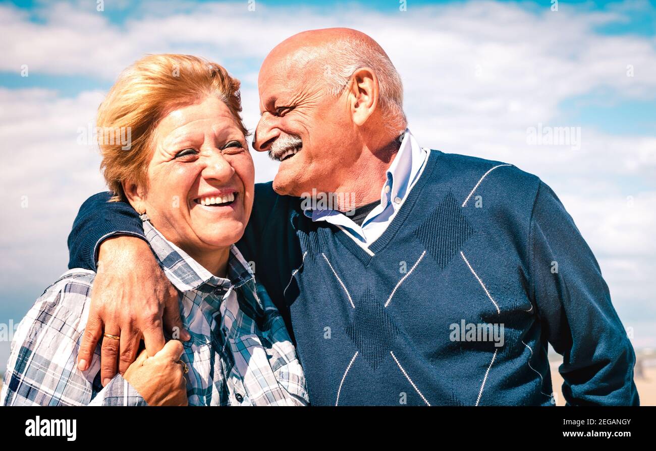 Felice coppia anziana innamorata godendo del tempo insieme - gioiosa stile di vita anziano e concetto di pensionamento con l'uomo che sussurra sulla donna orecchio Foto Stock