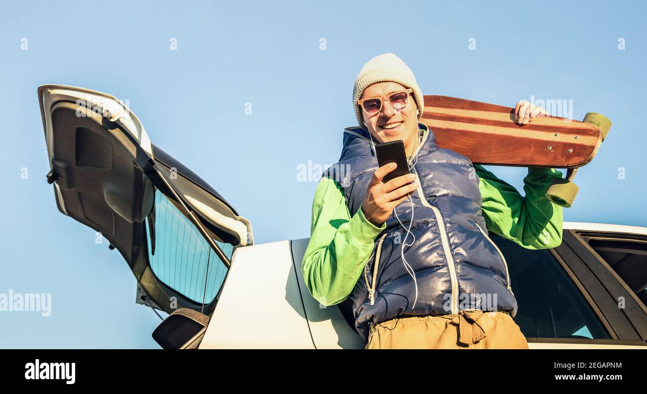 Giovane hipster bell'uomo con smartphone cellulare che ascolta la musica In auto viaggio - concetto di tecnologia moderna e wanderlust viaggio stile di vita Foto Stock