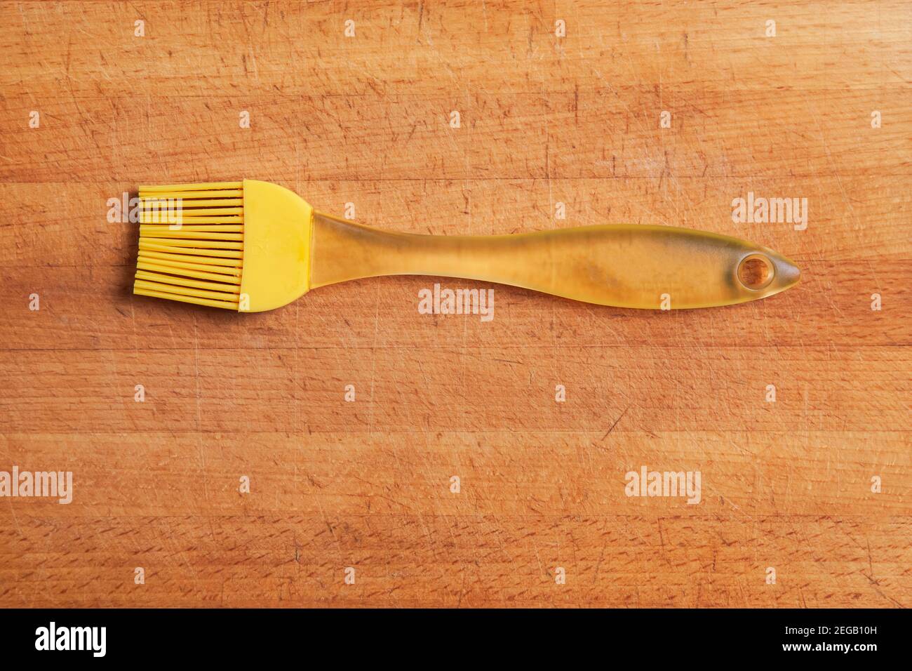 Una spazzola gialla in silicone per cucina è posizionata sul tagliere. Primo piano Foto Stock