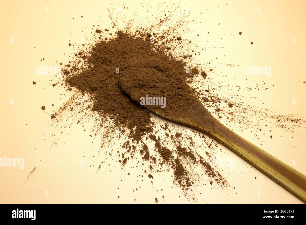 Un cucchiaio di legno con polvere di cacao puro sgrassato su marrone sfondo Foto Stock