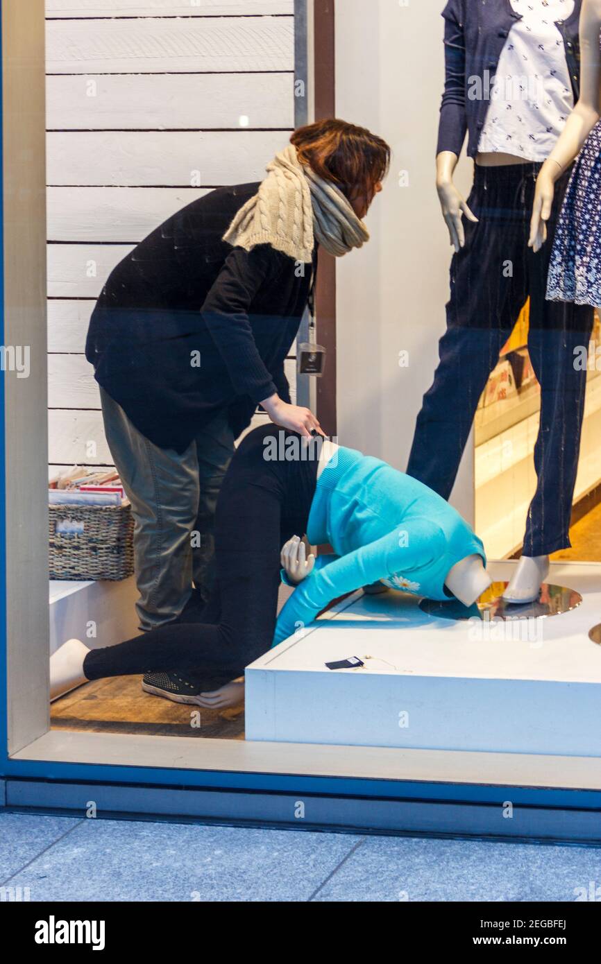 Un'impiegato femminile indossa un manichino nella finestra di un negozio di abbigliamento, Londra, Regno Unito Foto Stock