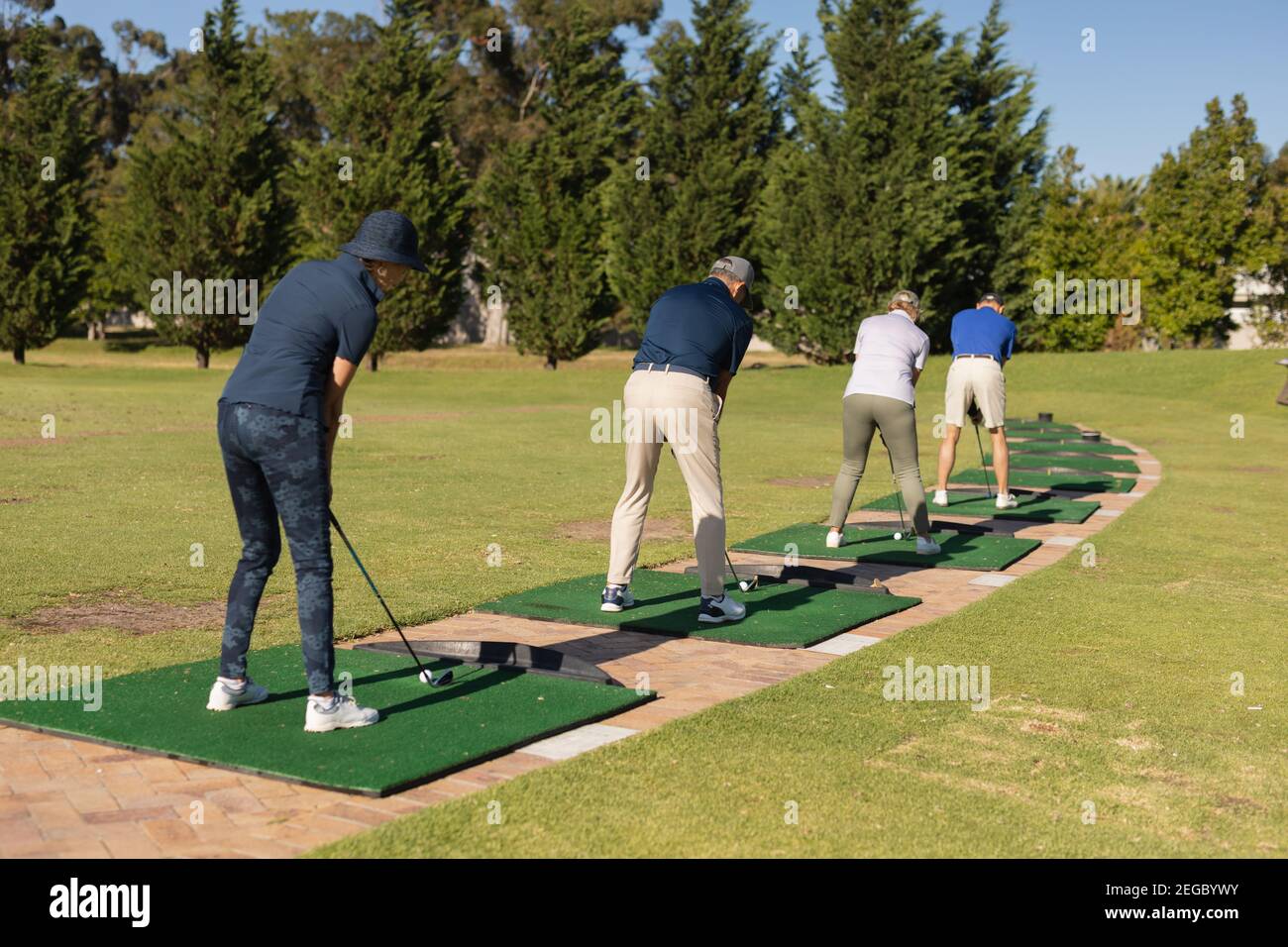 Tre uomini caucasici anziani e una donna che tiene il golf club preparazione per lo scatto sul verde Foto Stock