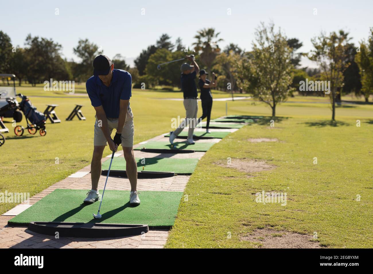 Due anziani caucasici e una donna che tiene il golf club preparazione per lo scatto sul verde Foto Stock