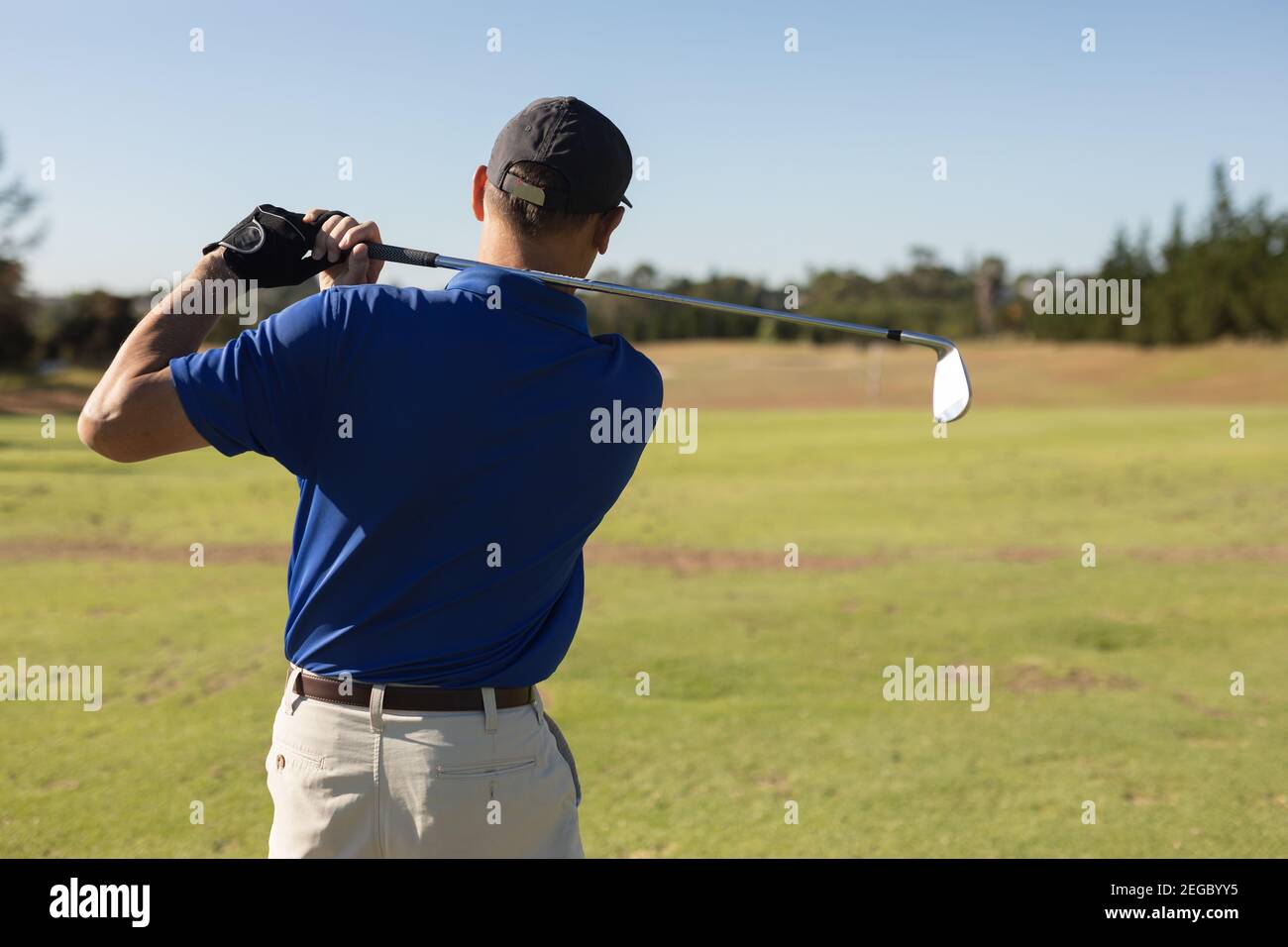 Uomo caucasico anziano che tiene il randello di golf che guarda la sfera dopo lo scatto Foto Stock