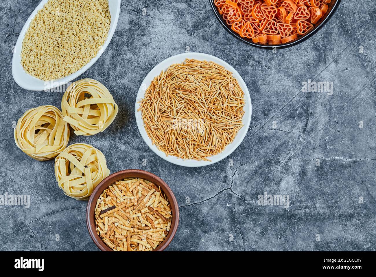 Vari tipi di pasta secca sullo sfondo marmoreo Foto Stock