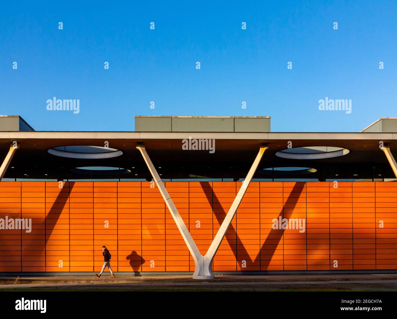 Uomo che cammina davanti a edifici moderni nel centro della città a. Borehamwood ed Elstree nel South Hertfordshire vicino a Londra Inghilterra Regno Unito Foto Stock