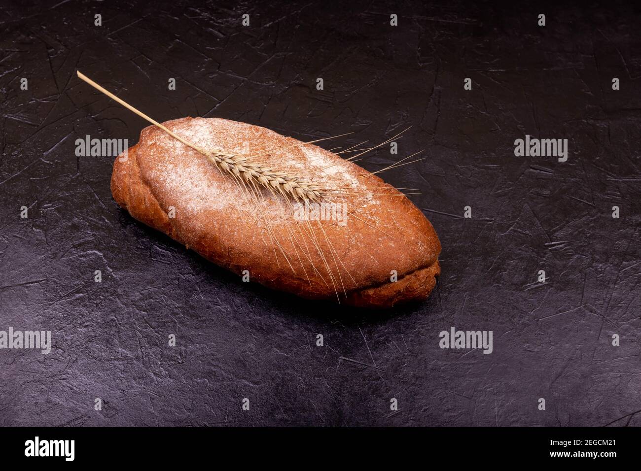 Pane fatto a mano su superficie nera in pietra. Pane fatto in casa appena sfornato. Foto Stock