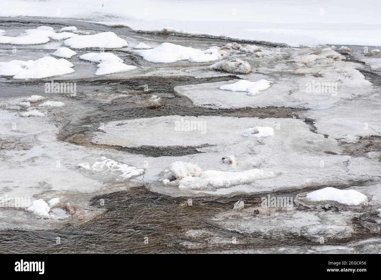 Fiume ghiacciato in inverno, neve e ghiaccio che si scioglie, ruscello fluente, sfondo della natura Foto Stock