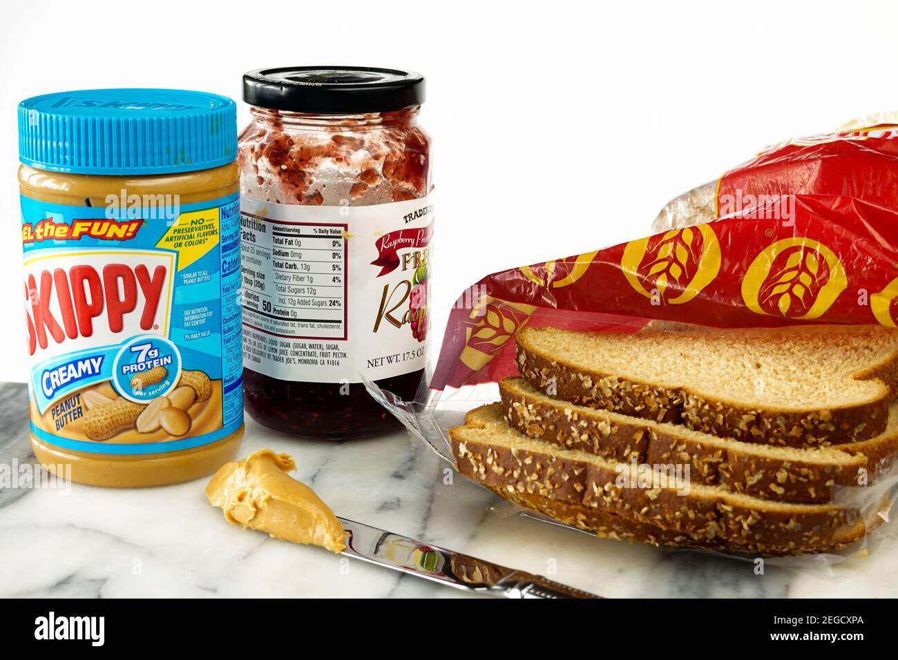 burro di arachidi skippy e un vasetto di gelatina di lampone o marmellata di  lamponi con pane integrale e burro di arachidi su un coltello Foto stock -  Alamy