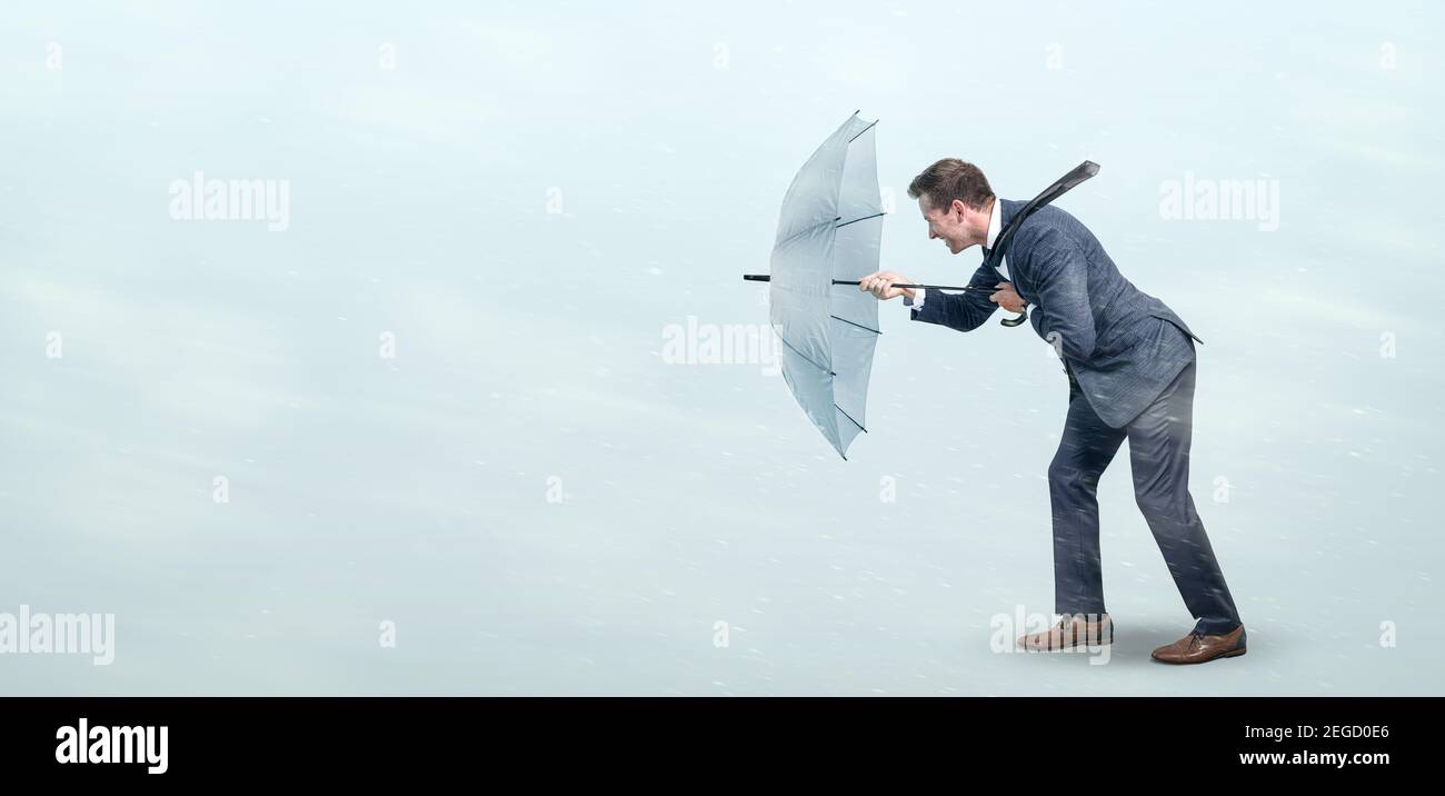 Uomo d'affari sfidando forte vento Foto Stock