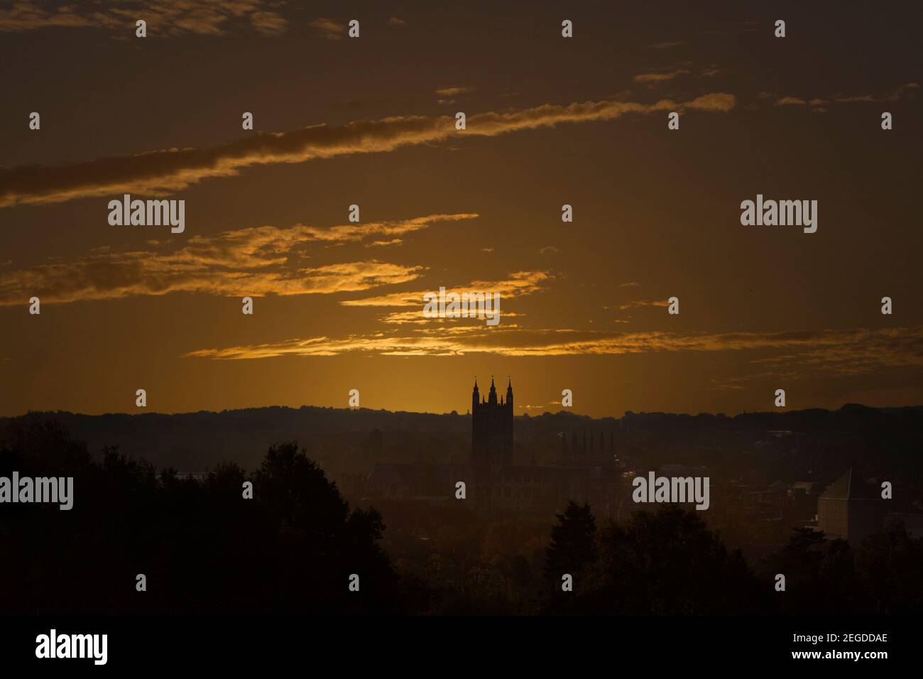 Vista sulla cima della collina dello skyline di Canterbury e del sole dorato che scompare in lontananza. Foto Stock