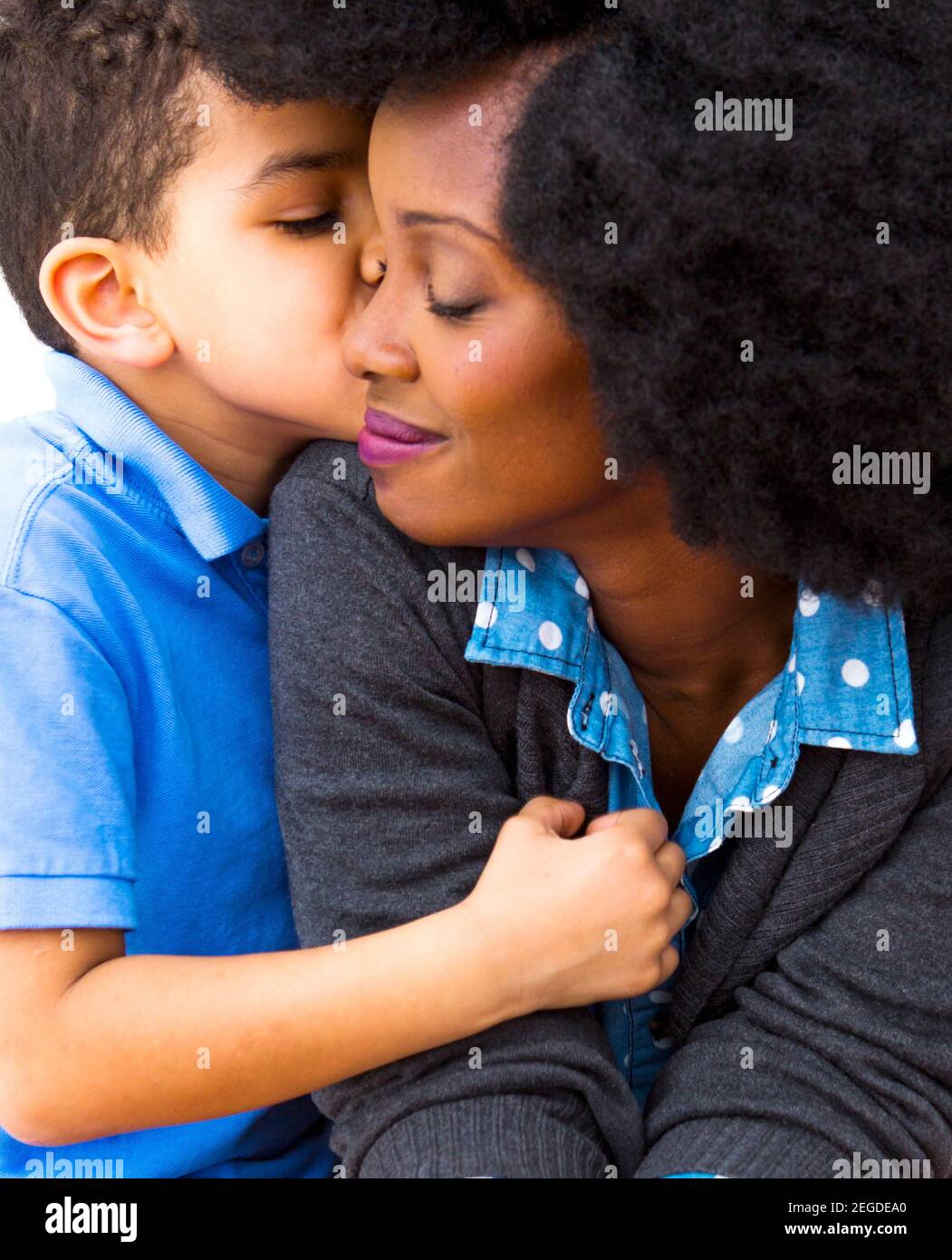 Un ragazzino abbraccia e bacia sua madre su guancia Foto Stock