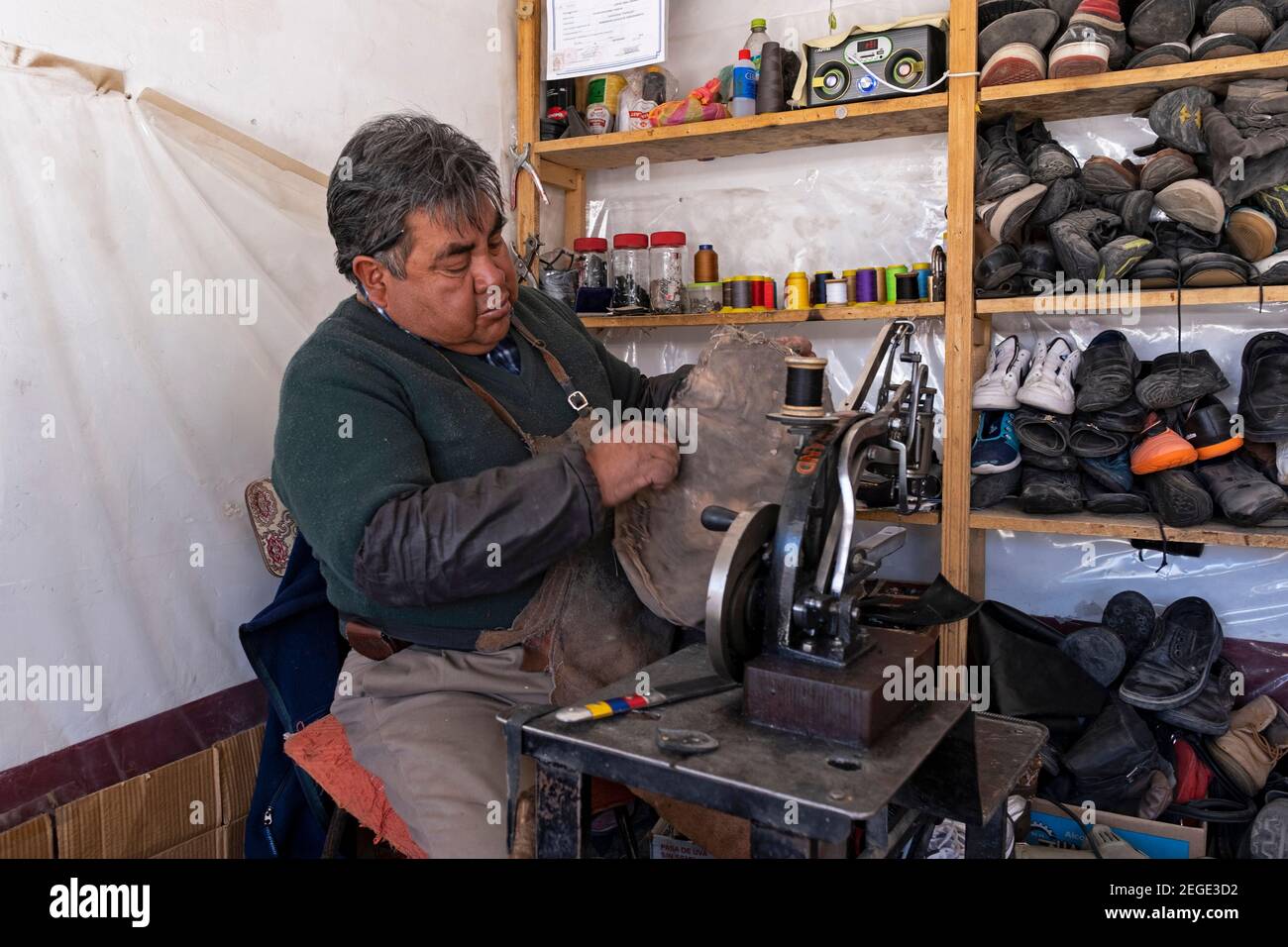 Ex-fashioned calzolaio boliviano con vecchia macchina da cucire mending scarpe in bancarella di mercato nella città di Uyuni, provincia di Antonio Quijarro, Potosí, Bolivia Foto Stock
