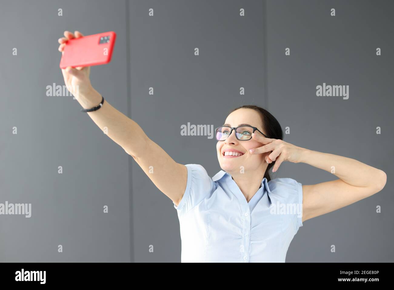 Donna con occhiali che sorridono e prendono selfie Foto Stock