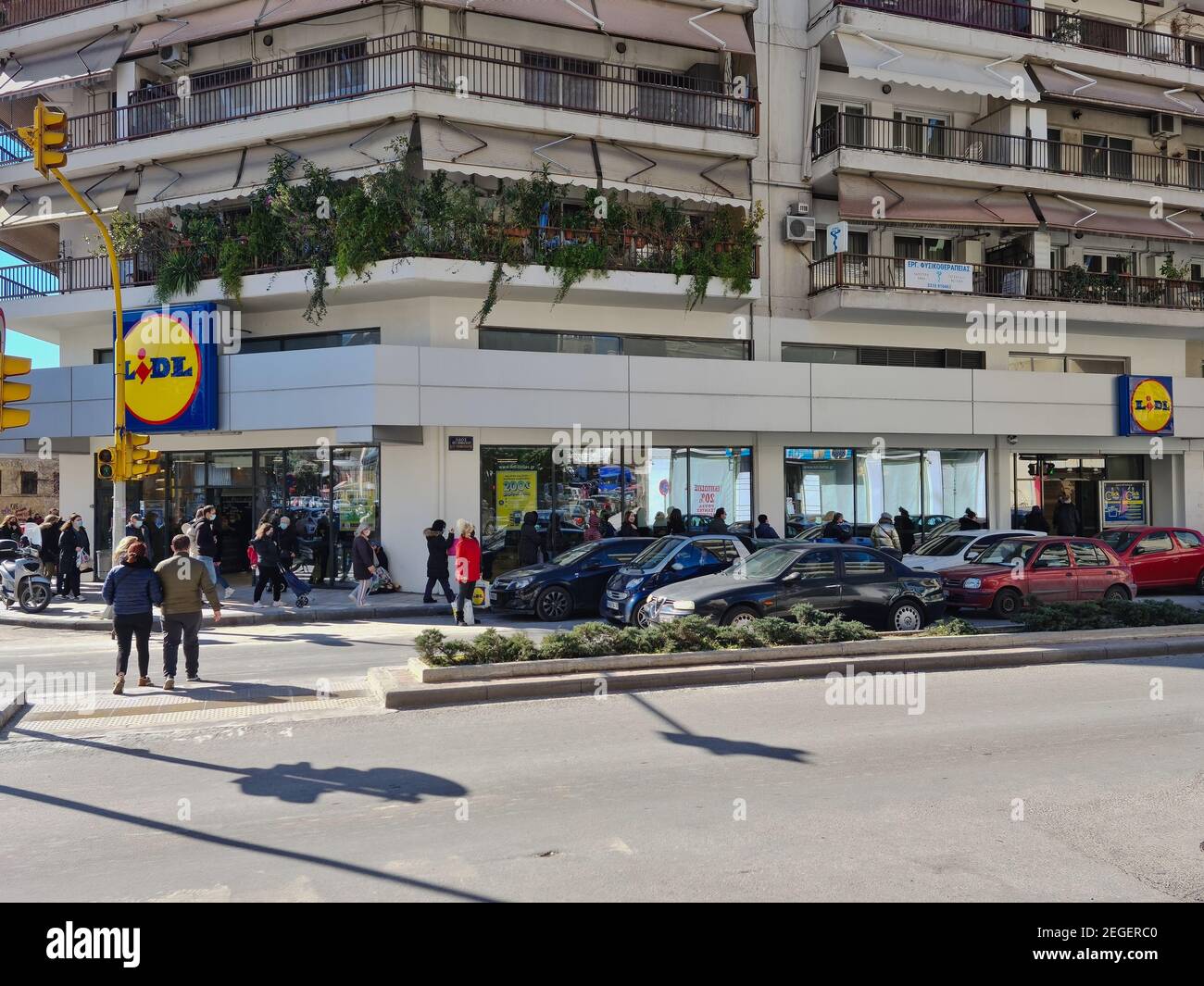 Salonicco, Grecia Febbraio - 18 2021: Folla con covid-19 maschere in coda  fuori super mercato. Un gran numero di persone con protezione del viso  aspettano in fila per entrare nel negozio di