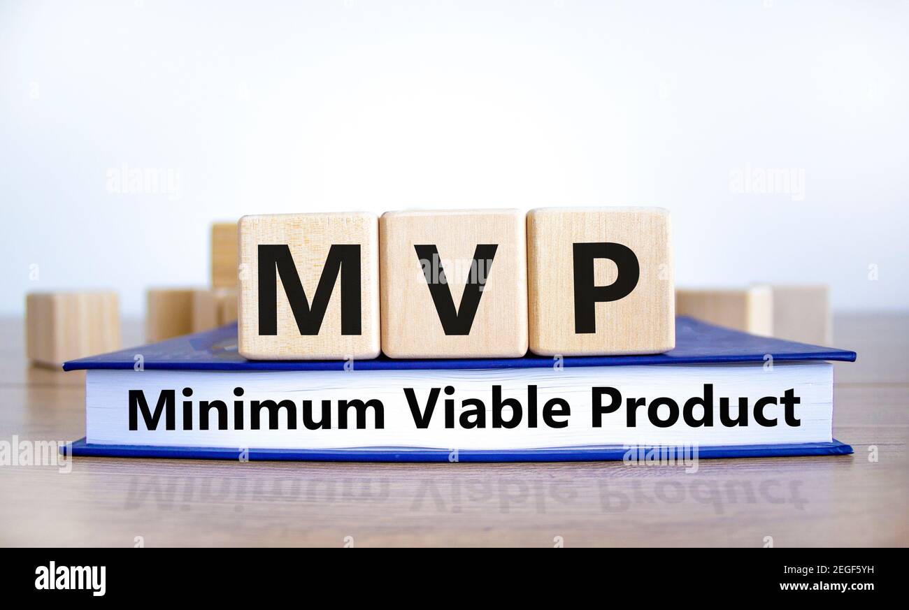 MVP, simbolo del prodotto minimo. Cubetti di legno su libro con parole MVP, prodotto minimo vitale. Splendido sfondo bianco. Azienda e MVP, minimo Foto Stock